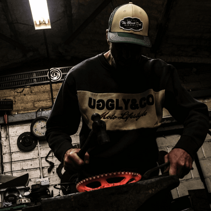 Person wearing a cap and sweatshirt with visible branding in a workshop setting