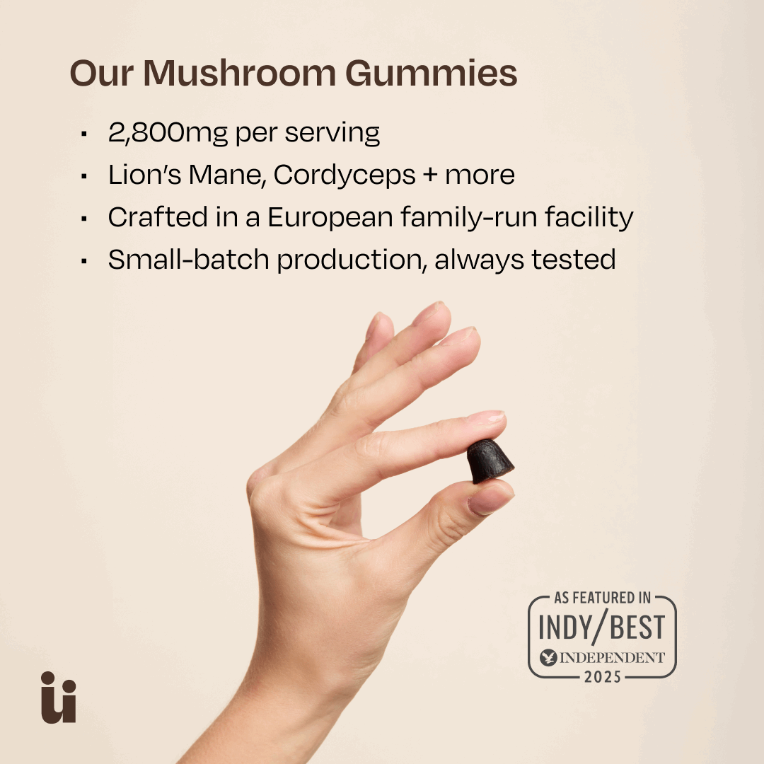 Hand holding a mushroom gummy with product details on a beige background