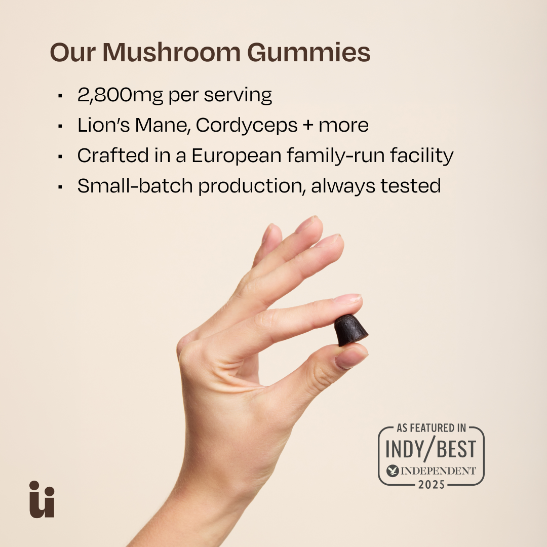 Hand holding a mushroom gummy with product details on a beige background