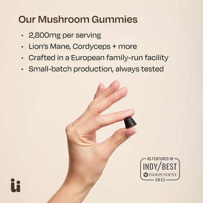 Hand holding a mushroom gummy with product details on a beige background