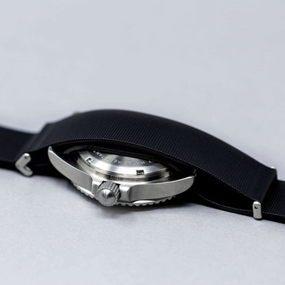 Close-up of a watch with a black strap on a light gray background