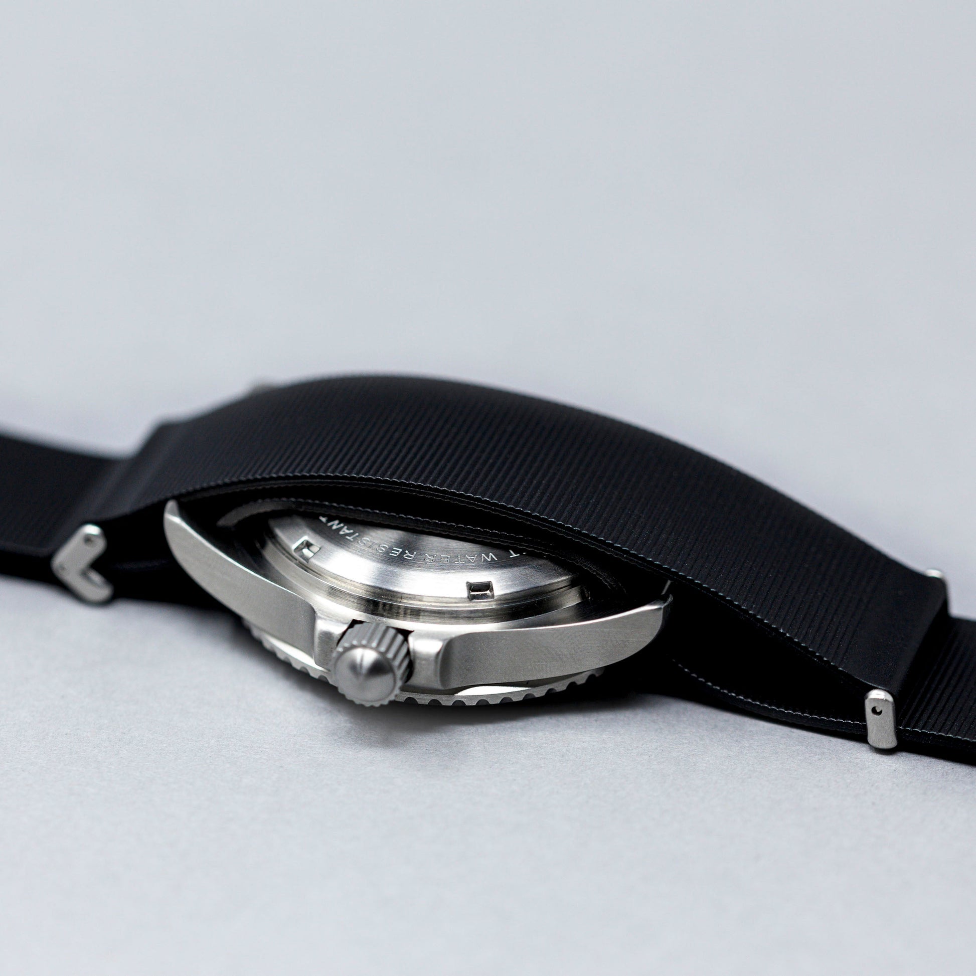 Close-up of a watch with a black strap on a light gray background