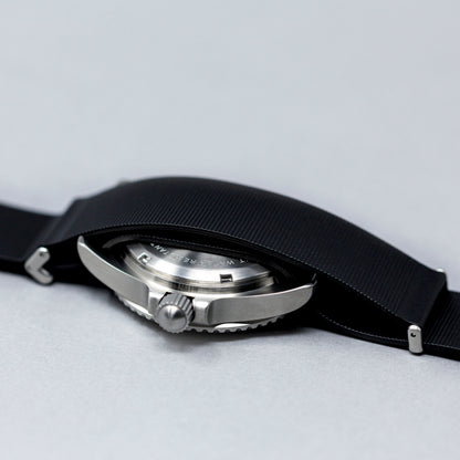 Close-up of a watch with a black strap on a light gray background