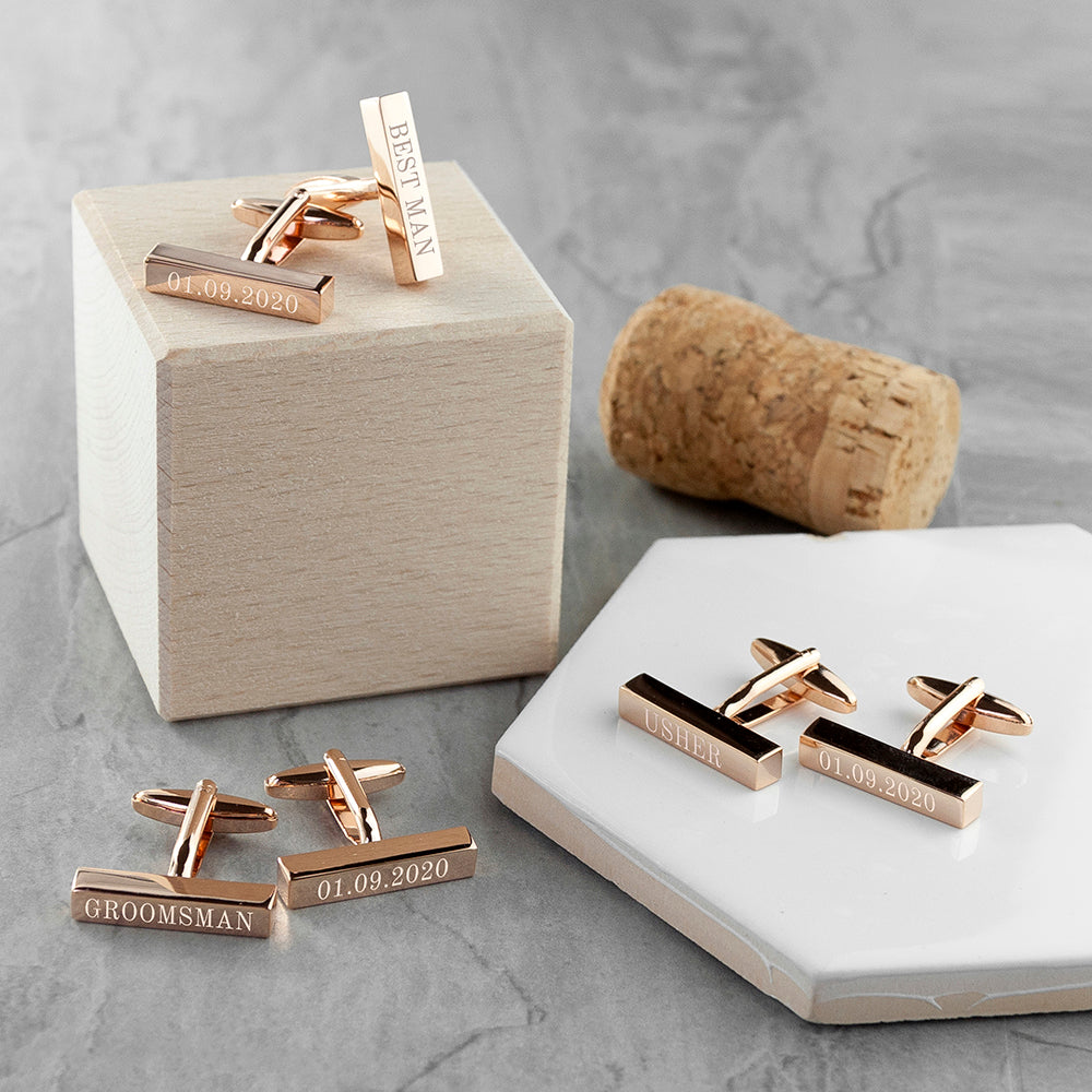 Rose gold cufflinks with engravings on a gray surface
