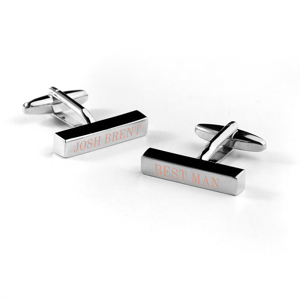 Pair of silver cufflinks with engraved names on a white background