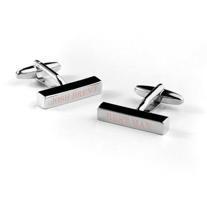 Pair of silver cufflinks with engraved names on a white background