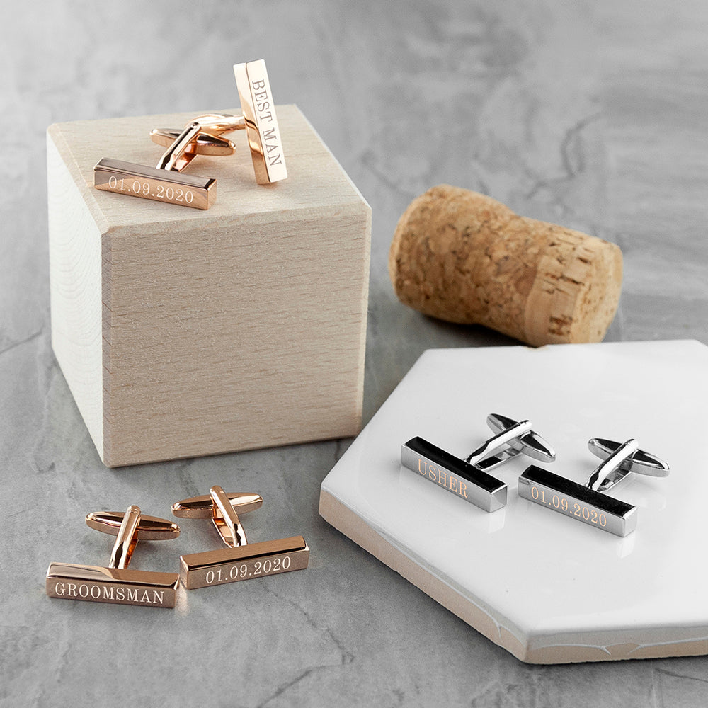 Rose gold and silver cufflinks with engraved text on a gray surface.