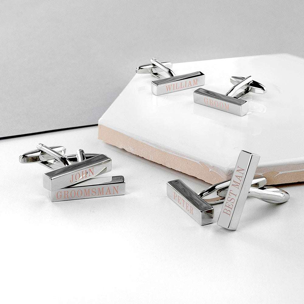 Silver cufflinks with engraved text on a white surface