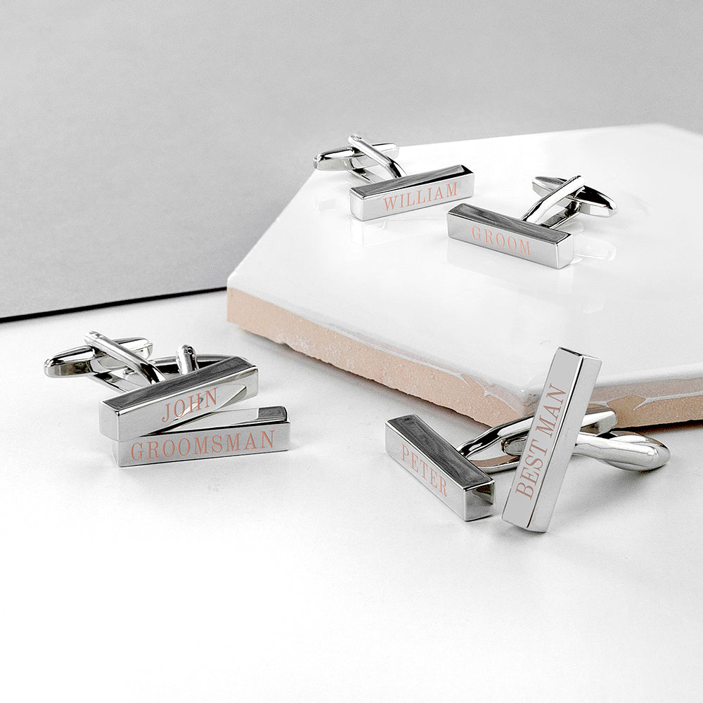 Silver cufflinks with engraved text on a white surface