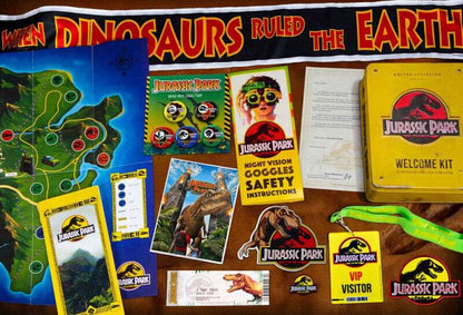 Jurassic Park themed items including a map, brochures, and safety instructions on a wooden surface.