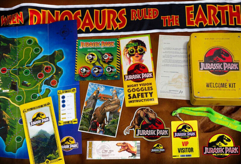 Jurassic Park themed items including a map, brochures, and safety instructions on a wooden surface.