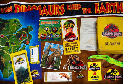 Jurassic Park themed items including a map, brochures, and safety instructions on a wooden surface.