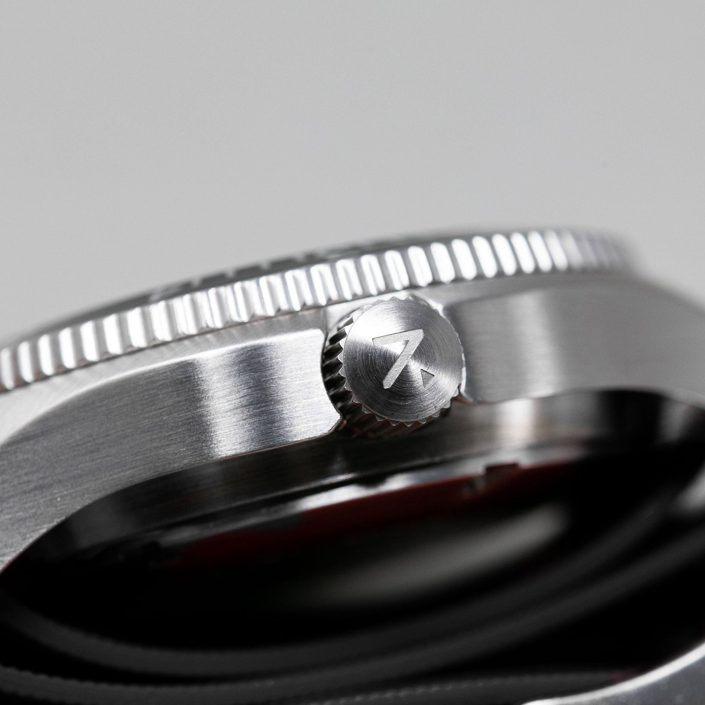 Close-up of a silver watch with a brand logo on a gray background