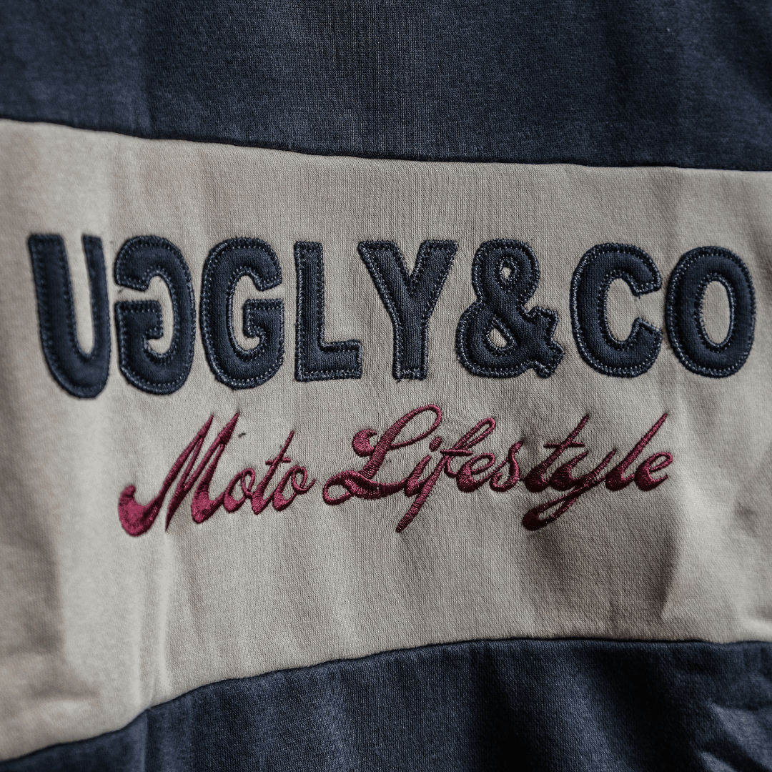 Text 'UGLY&CO Moto Lifestyle' on a fabric background