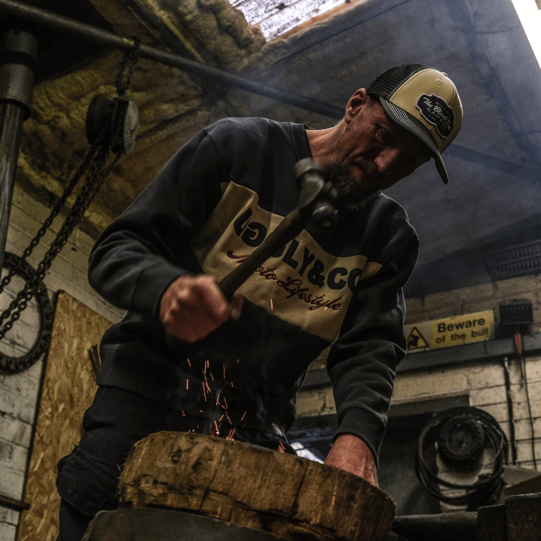 Man working with a hammer and an anvil in a workshop setting